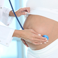 Doctor holding stethoscope on pregnant woman's stomach