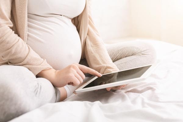 pregnant woman reading on tablet